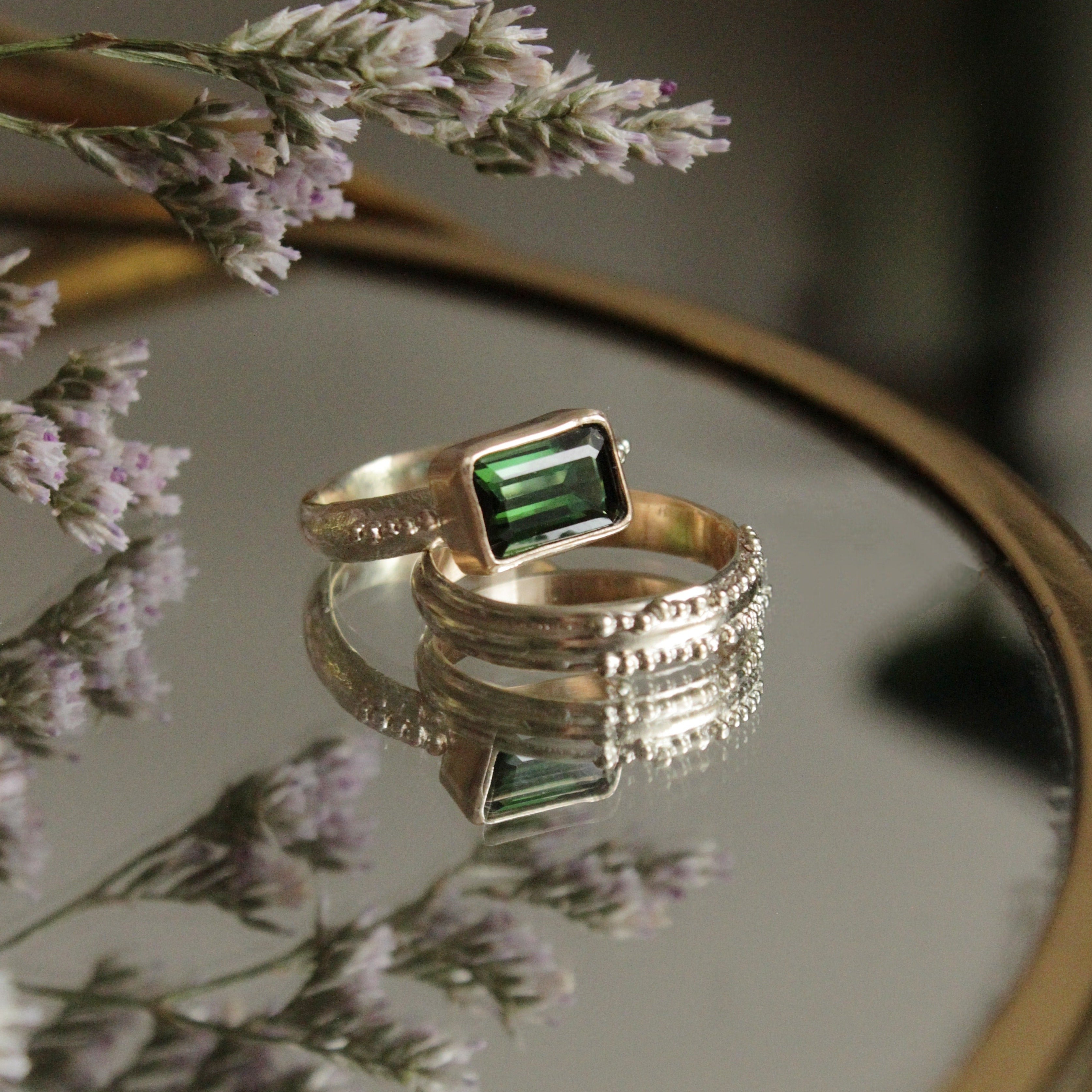 A stunning Green Tourmaline stone set on a 9 ct gold band. The band features an organic textures with tinny gold granules delicately framing the centrepiece stone.. Hand crafted alternative engagement ring by Josie Mitchell jewellery. Made in Frome, Somerset.