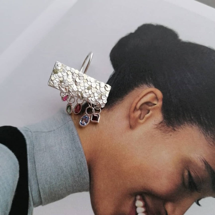 The gorgeous Calypso earrings are one of my favourite creations! They feature 10 brightly coloured natural Sapphires that hang from the bottom of the Siren plates to create a beautiful shimmer and chime. Delicate hand crafted siren details make this pair of earrings entirely unique and magical. Their otherworldly appearance is entirely one-of-a-kind and unique, hand crafted by Josie Mitchell Jewellery in her Bournemouth studio. 