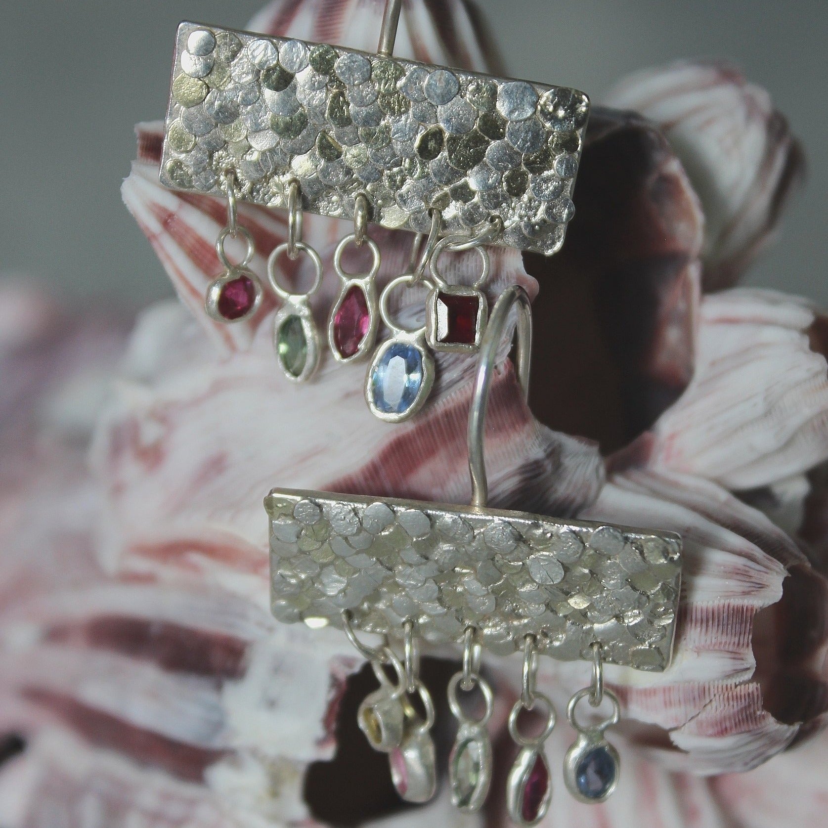 The gorgeous Calypso earrings are one of my favourite creations! They feature 10 brightly coloured natural Sapphires that hang from the bottom of the Siren plates to create a beautiful shimmer and chime. Delicate hand crafted siren details make this pair of earrings entirely unique and magical. Their otherworldly appearance is entirely one-of-a-kind and unique, hand crafted by Josie Mitchell Jewellery in her Bournemouth studio. 