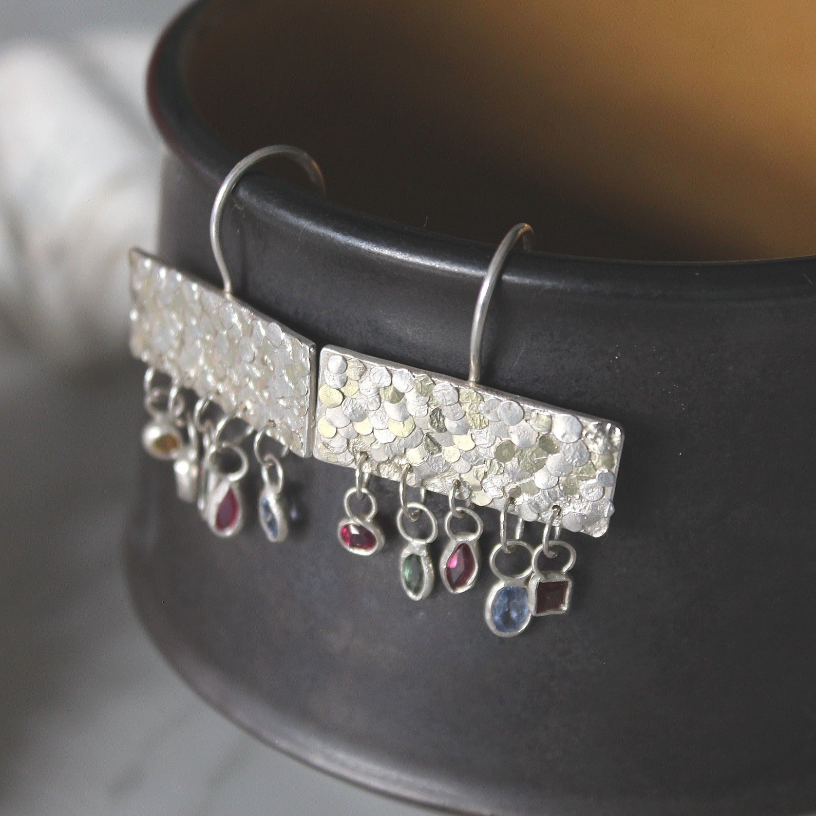 The gorgeous Calypso earrings are one of my favourite creations! They feature 10 brightly coloured natural Sapphires that hang from the bottom of the Siren plates to create a beautiful shimmer and chime. Delicate hand crafted siren details make this pair of earrings entirely unique and magical. Their otherworldly appearance is entirely one-of-a-kind and unique, hand crafted by Josie Mitchell Jewellery in her Bournemouth studio. 